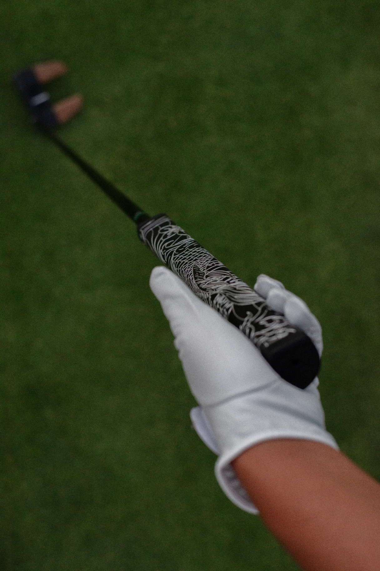 A gloved hand holding the Kaiyen putter grip on the course
